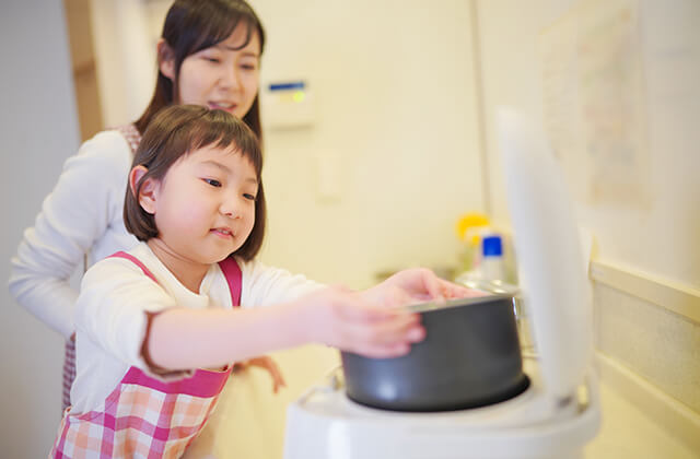 母親が見守る中、子どもが炊飯器をセット